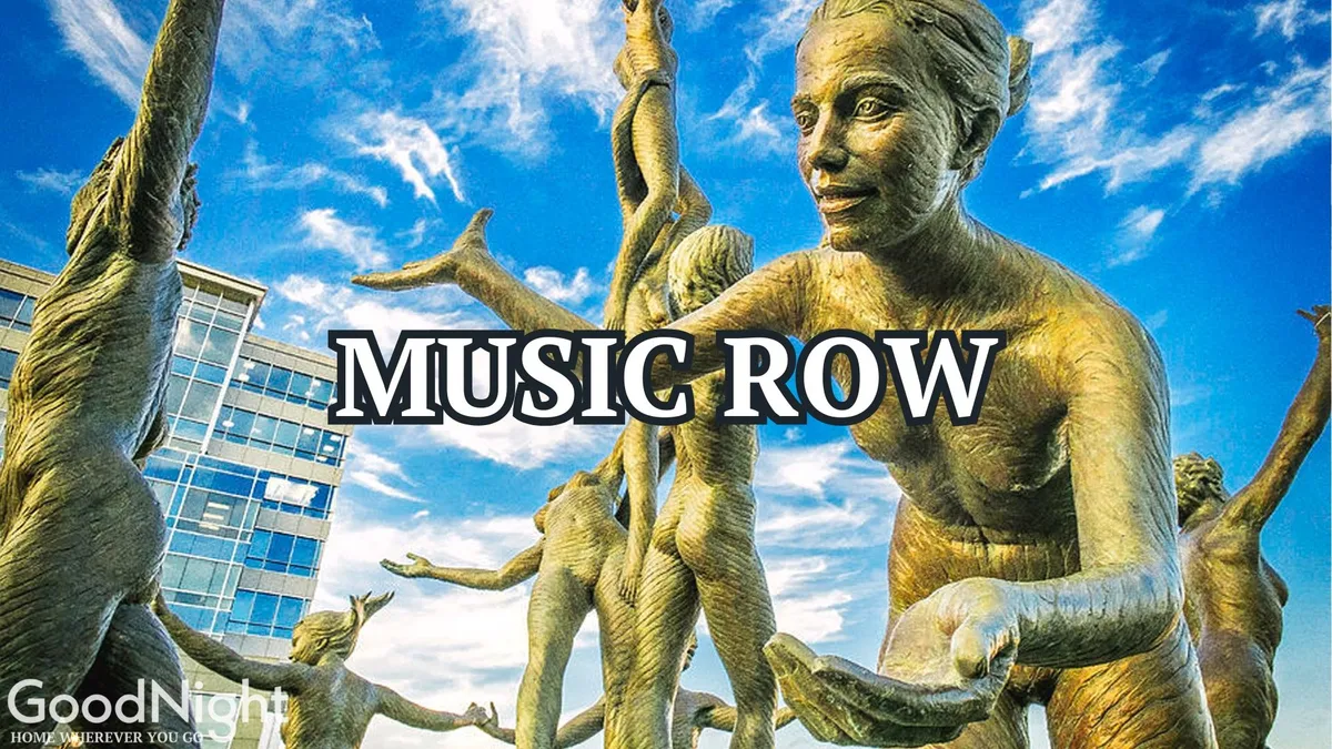 Outdoor sculptures rise against the sky with buildings in the background. People are actively exploring the art, taking photos, and attending what appears to be a music or art event, creating a lively urban scene.